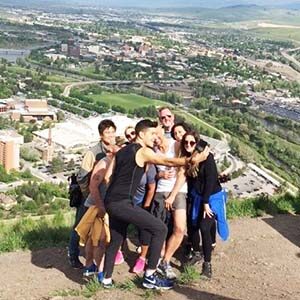 A teambuilding group posing at the top of a small mountain