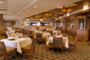 The interior of EMC Club in Fenway Park. It has tables and chairs with a yellow patterned carpet