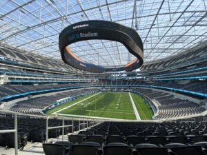 The new SoFi Stadium. A football field is set up under glass and scaffolding on the ceiling.