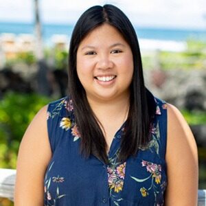 A portrait of Victoria Bernardo. She is an Asian woman with a blue, floral-patterned sleeveless blouse.