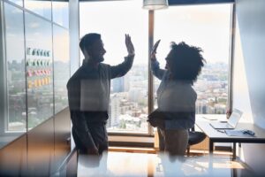 Two coworkers high fiving in an office.