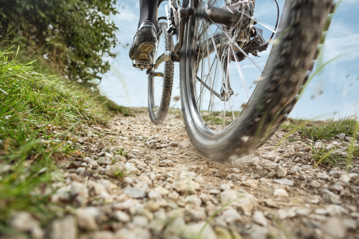 A rocky bike path with a low view of the bottom of a bike.