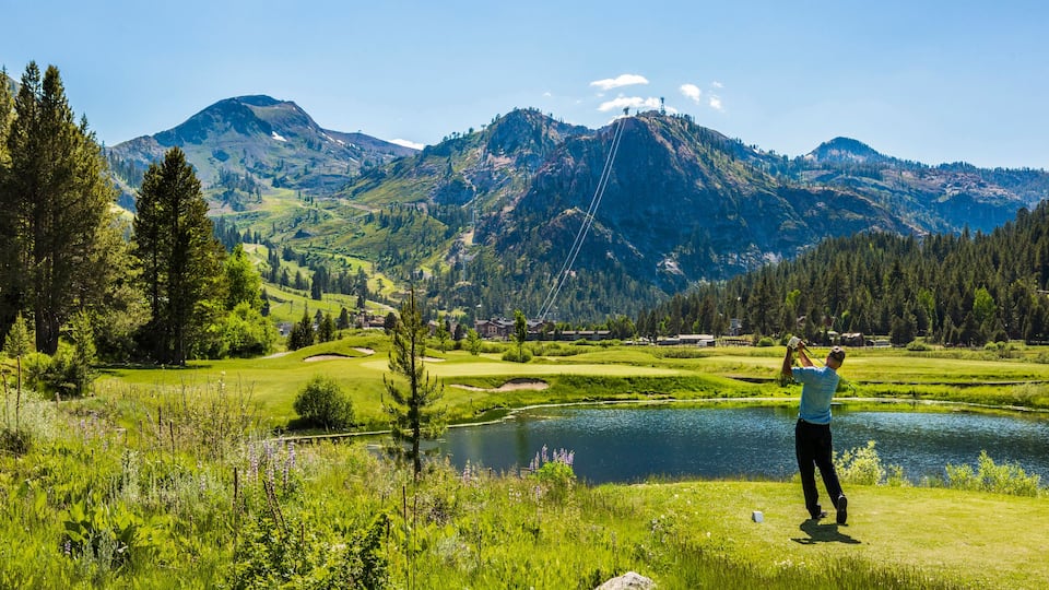 man golfing at golf course with mountains in foreground