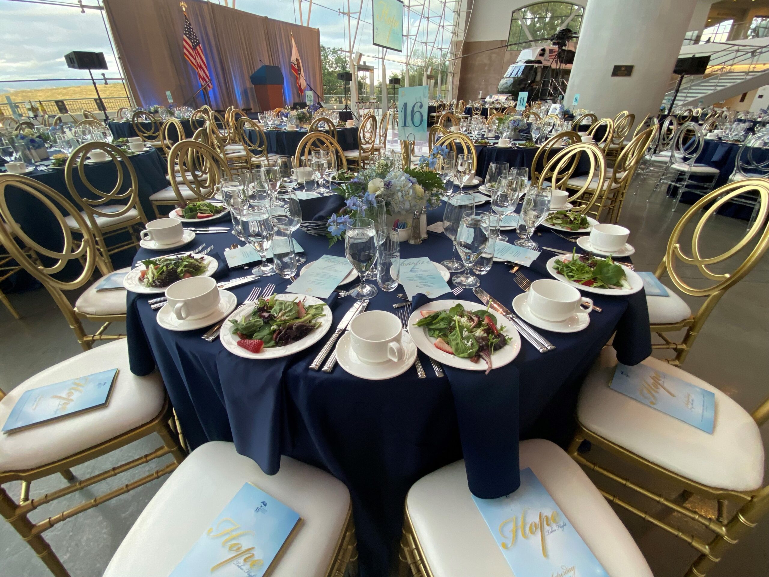 table with blue sheet surrounded by white chairs