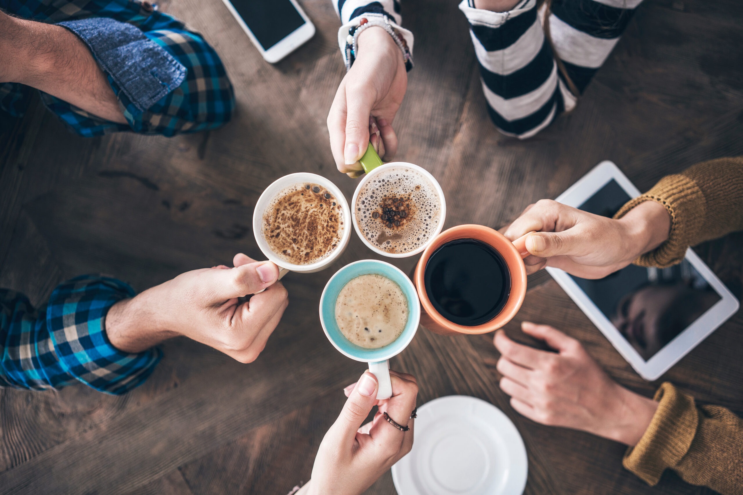 four people clinking mugs