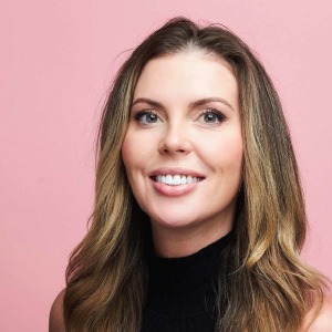 woman smiling in front of pink background