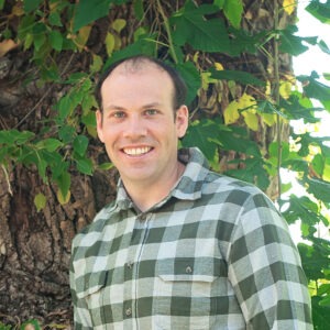 man in green plaid long sleeve dress shirt smiling