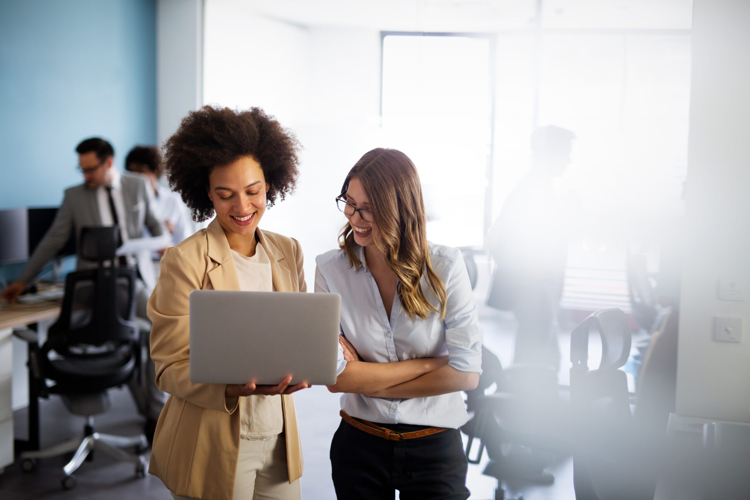 woman showing laptop screen to another woman