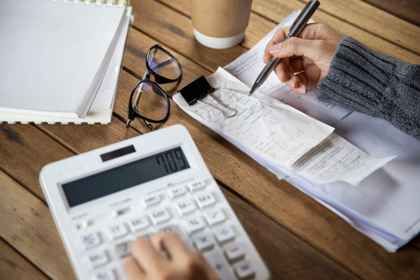 person typing on calculator and writing on notepad