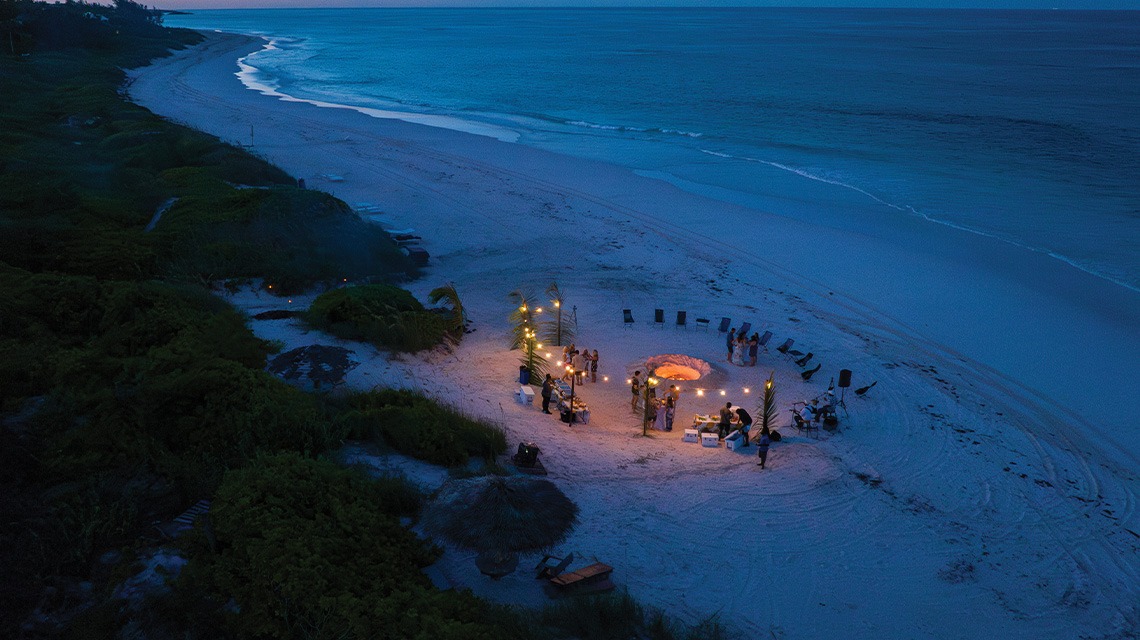 People at fireside event on beach at Eleven Bahamas