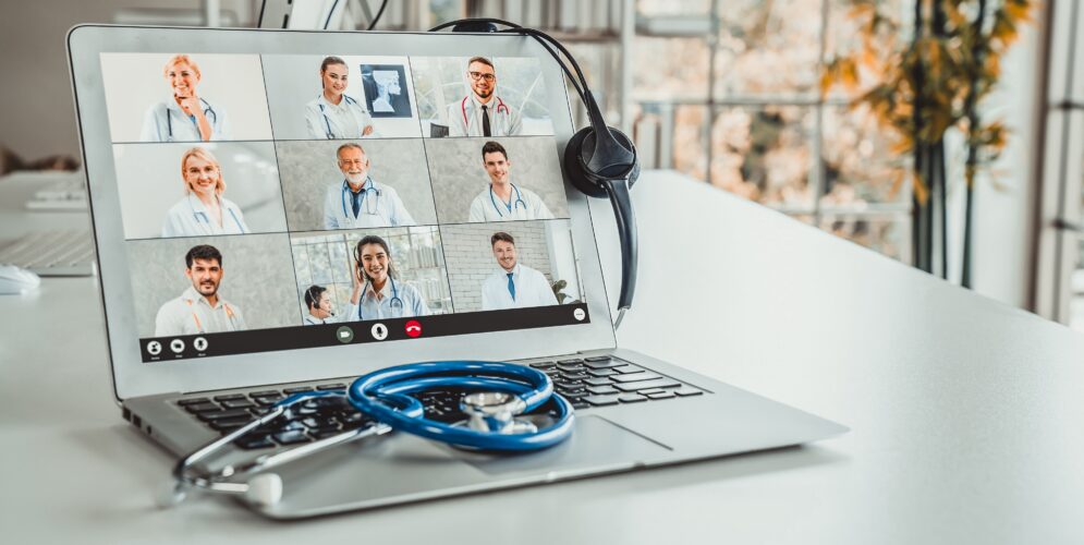 laptop screen shows doctors on video call