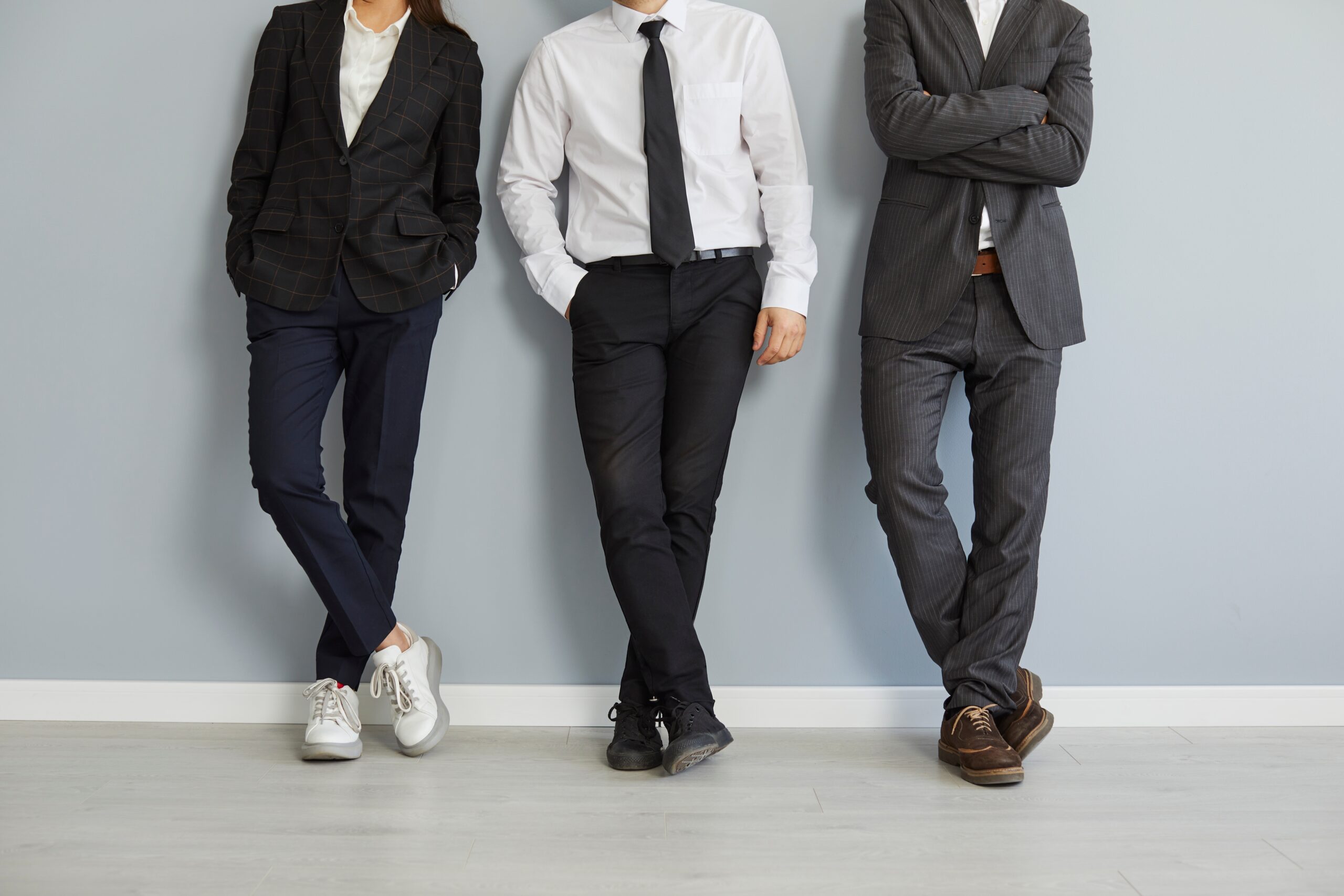 Three businesspeople in formal suits paired with casual shoes